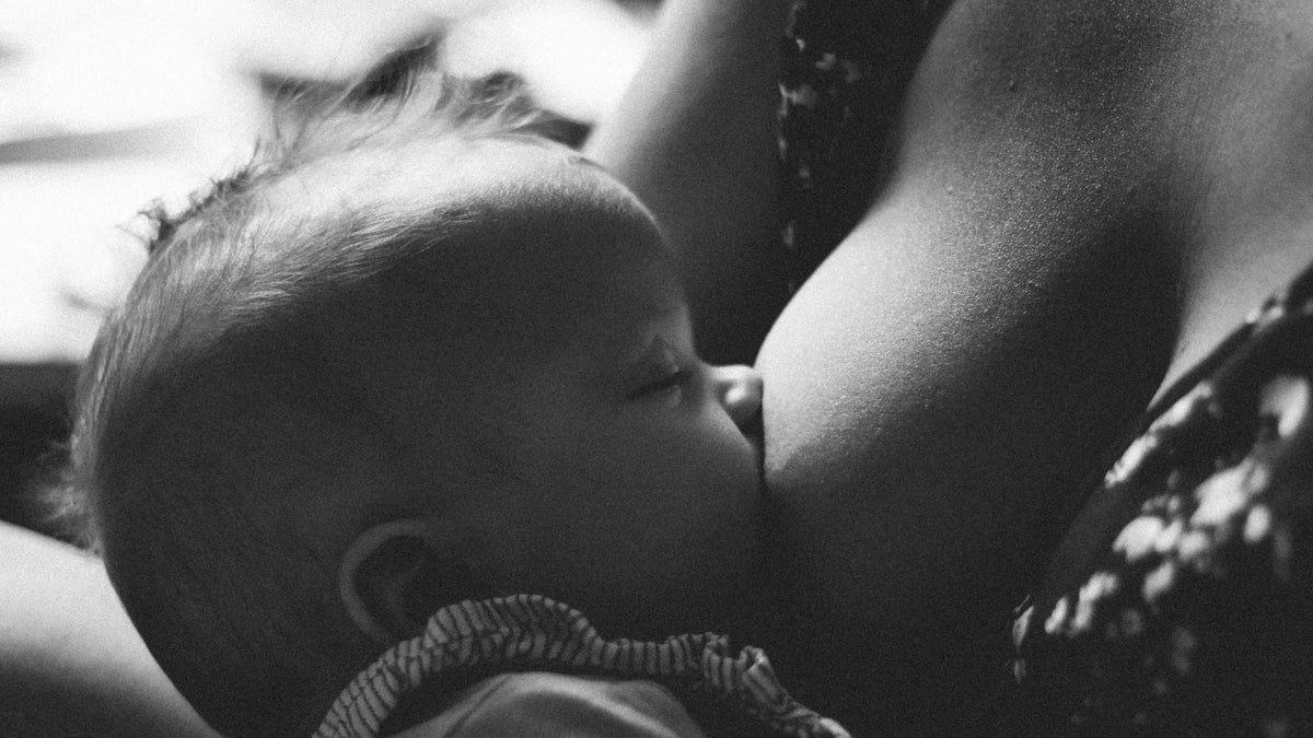 Photo en noir et blanc d'une maman allaitant son bébé illustrant l'article de blog : la santé mentale des jeunes mamans et l'importance de prendre soin de soi de Mama Hangs
